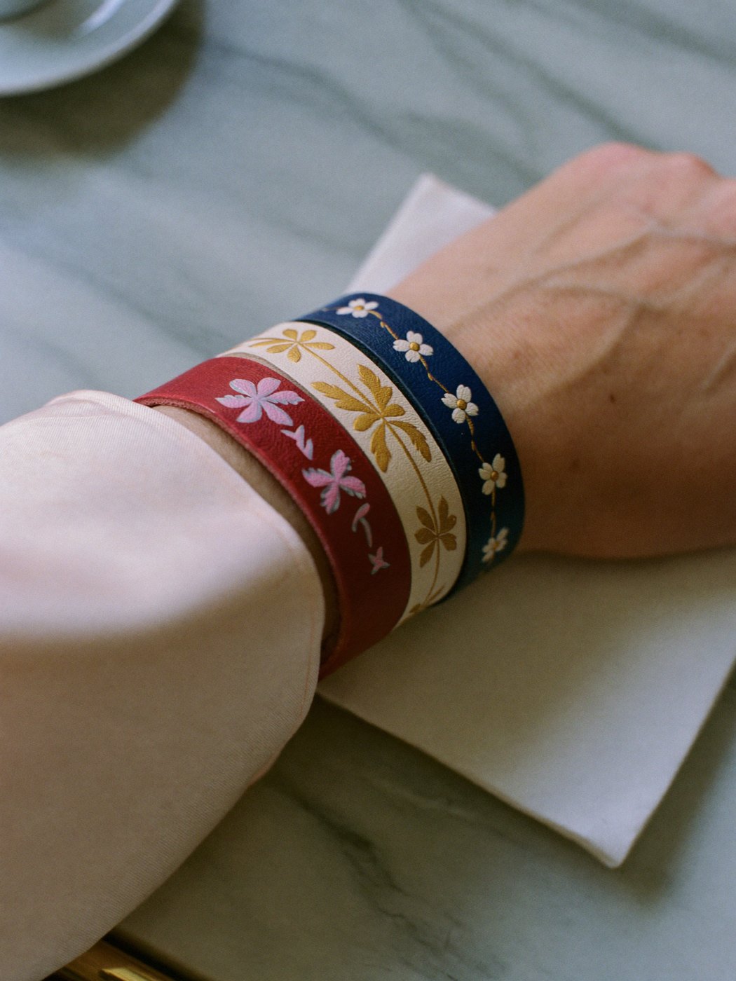 Three hand-painted leather bracelets resting on a café table