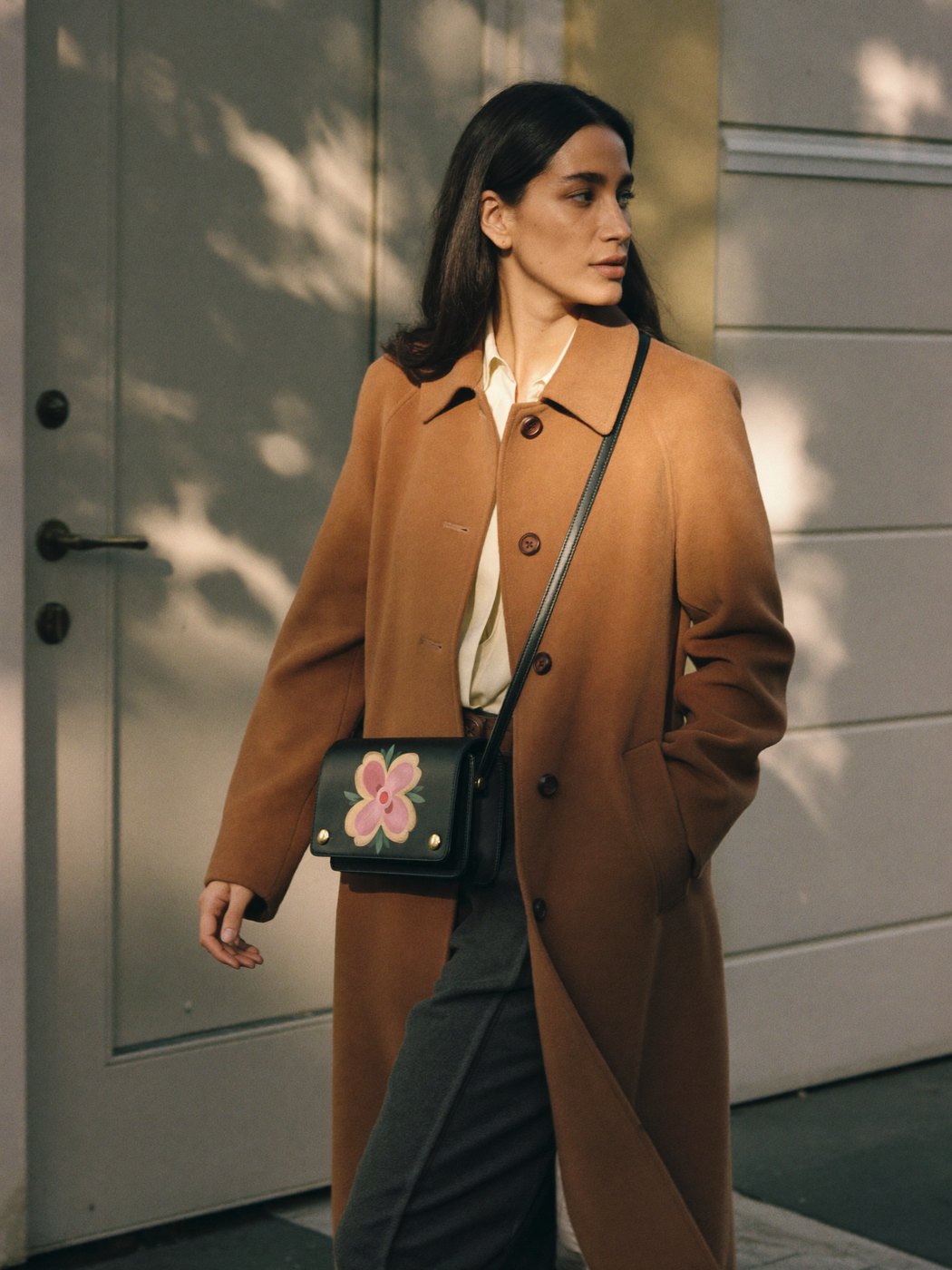 Hand-painted crossbody worn through a sunlit doorway